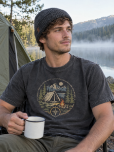 Man at a lakeside campsite wearing a charcoal outdoor camping graphic t-shirt